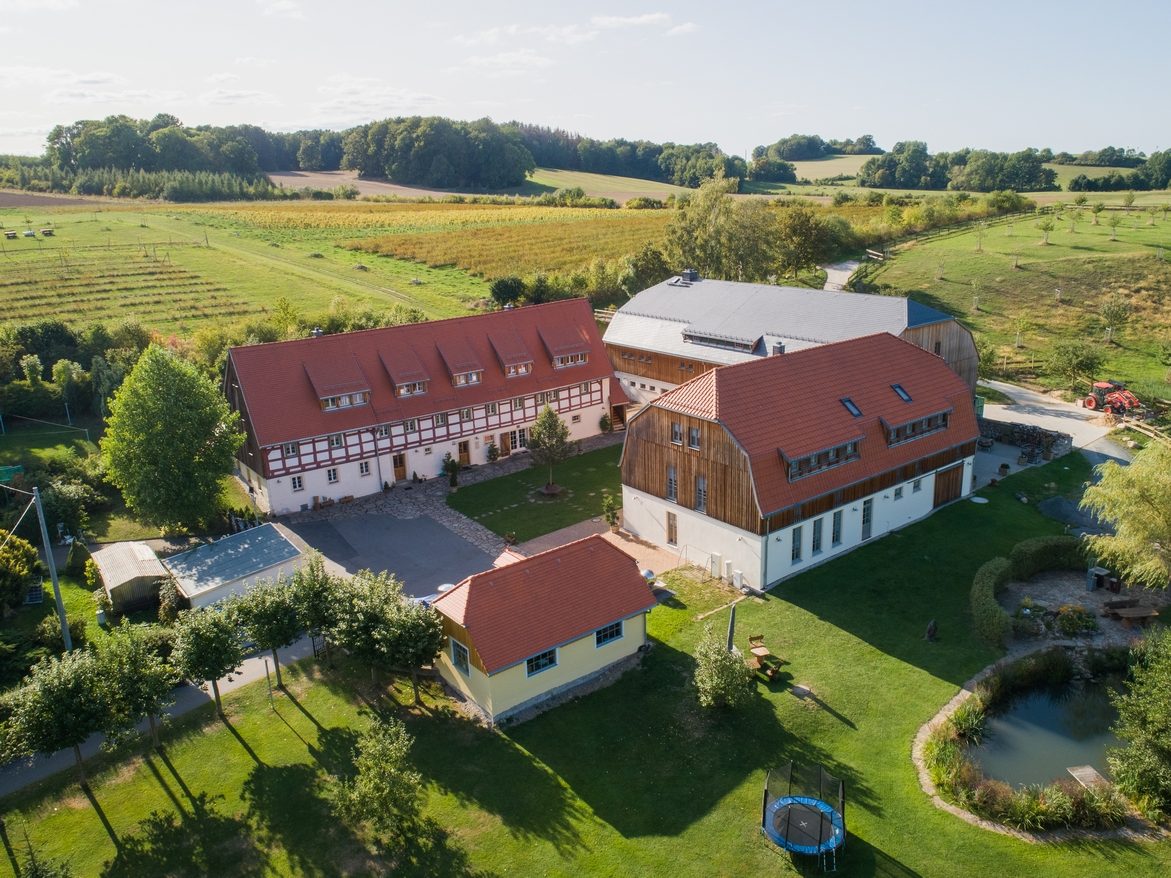 Luftaufnahme des Dreiseithofs Sohra: Fachwerkhaus, Gästehaus und Teich zwischen Feldern